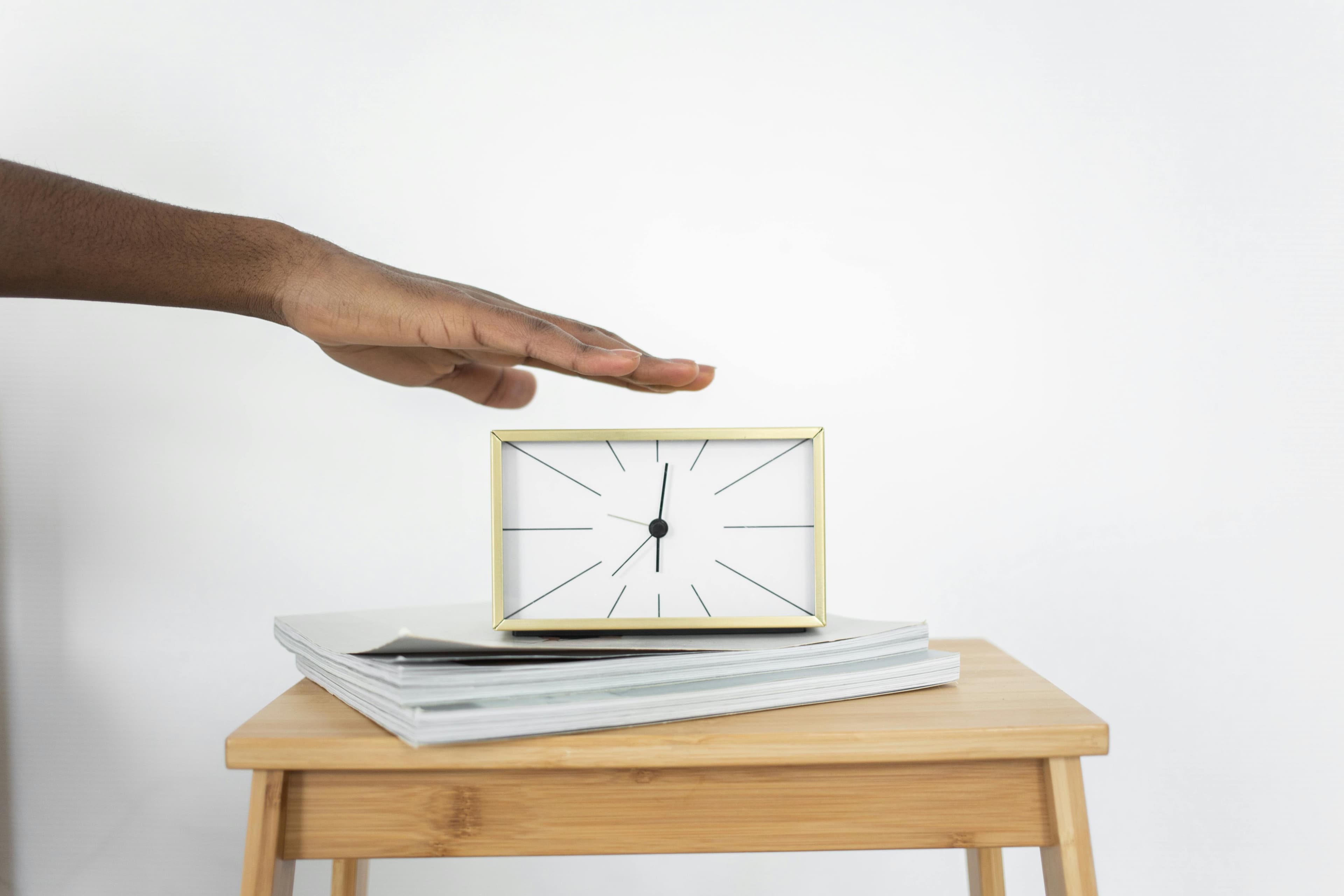Person with hand over clock representing procrastination